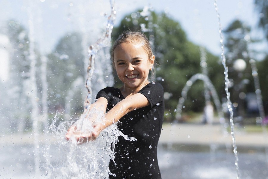 A young girl joyfully plays in a fountain at a water playground in Dubai