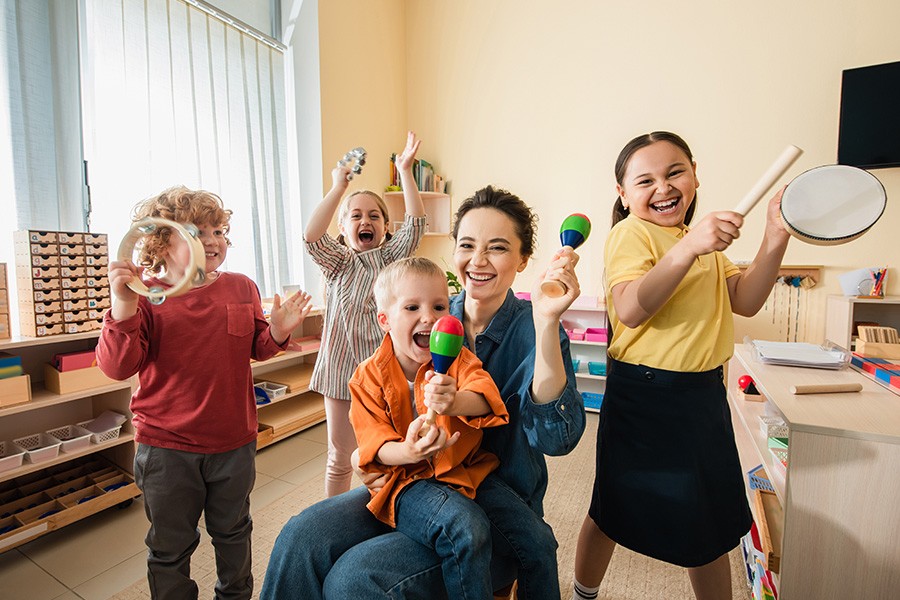 A group of children joyfully playing in a classroom, engaging in music-related activities