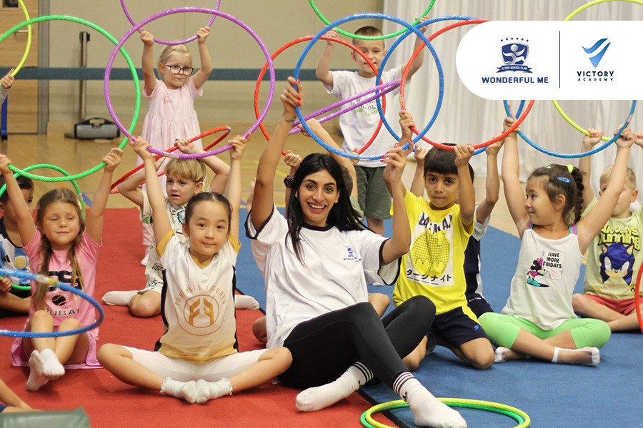 A lively group of kids playing with hula hoops in a gym during Winter Camp in Dubai