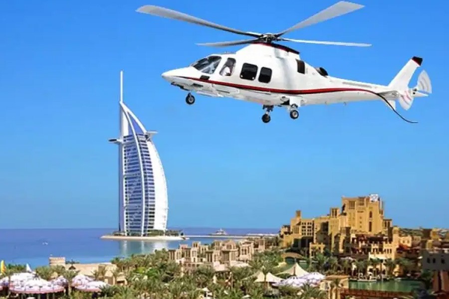 Helicopter flying over Dubai's beach, with the Burj visible, highlighting the excitement of dune buggies and helicopter rides