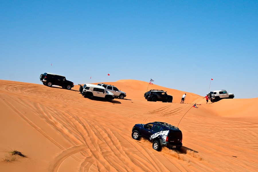 A lineup of vehicles navigating the sandy desert, capturing the essence of adventure in Dubai with dune buggies and more