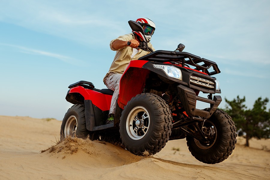 A man rides a red ATV across sandy dunes, showcasing Dubai's thrilling adventure scene