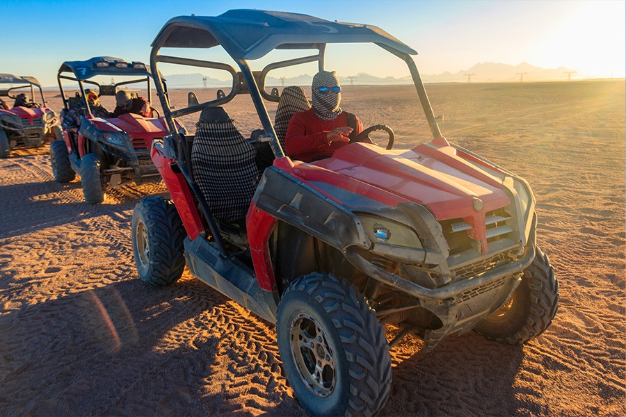 Excited riders on four wheelers zooming across the sandy dunes of Dubai, embracing the adventure of the desert