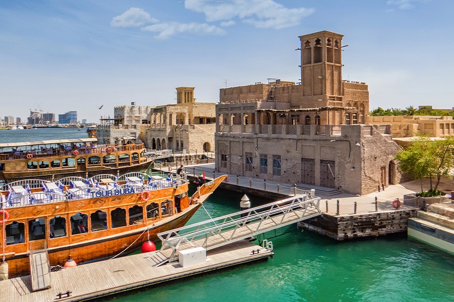 A boat rests at the dock near a towered building, marking Dubai National Day at Al Seef