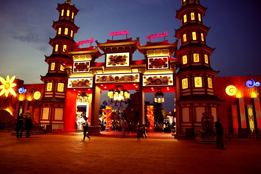 A vibrant building illuminated at night, with families strolling around, enjoying the sights at Global Village Dubai