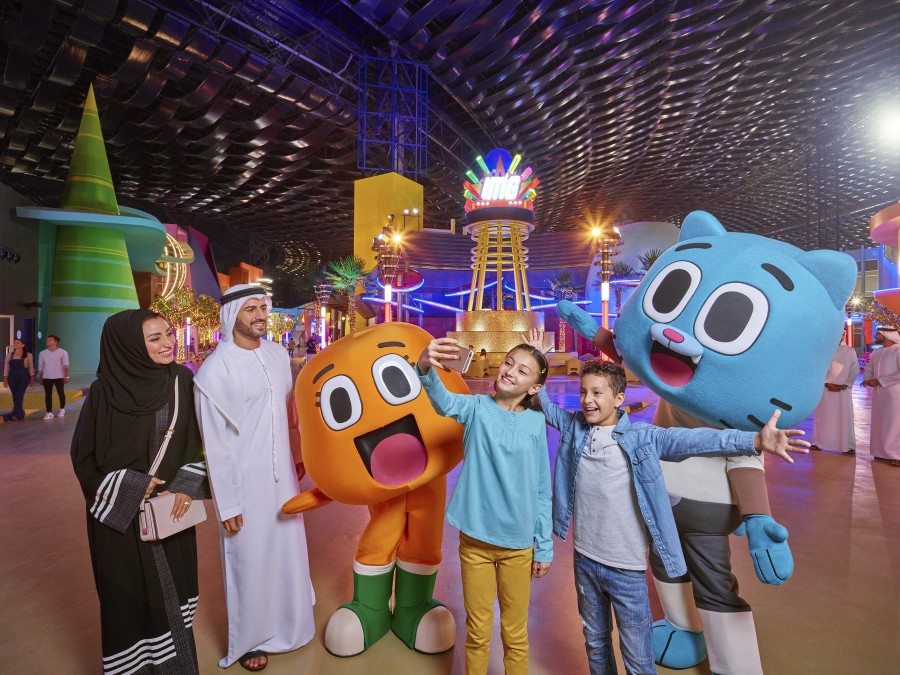 A cheerful family poses with colorful characters at IMG Worlds of Adventure in Dubai, capturing a fun-filled moment