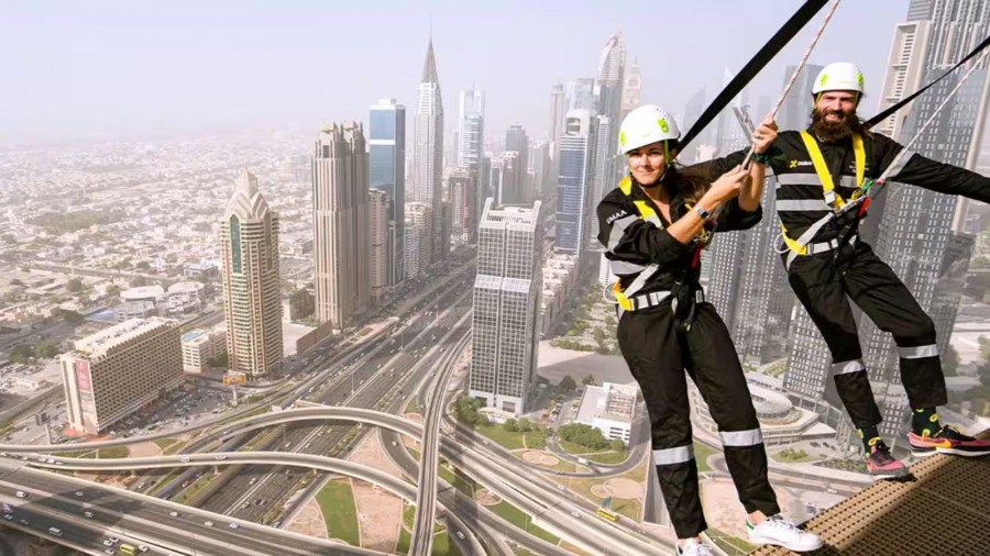 Two people balancing on a rope with a stunning city skyline of Dubai in the background, perfect for family adventures