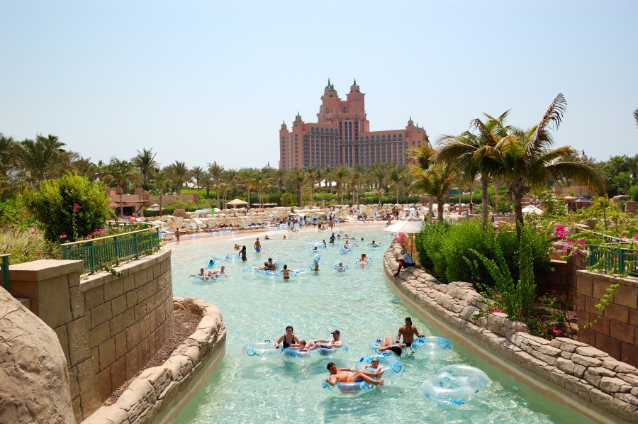 Families having fun at a large water park in Dubai, splashing around in the pools and enjoying the slides