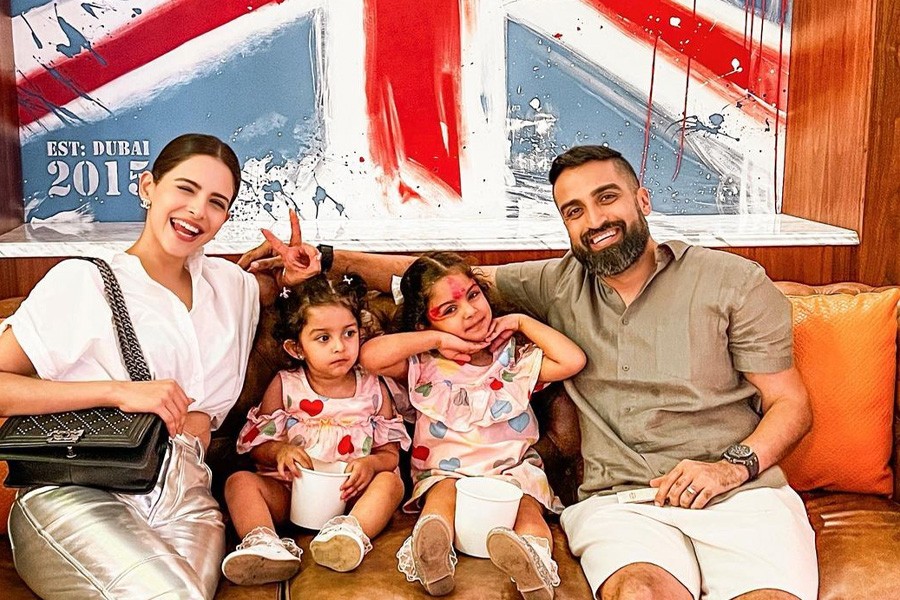 A happy family smiles for a photo in front of a British flag, showcasing their love for travel and culture