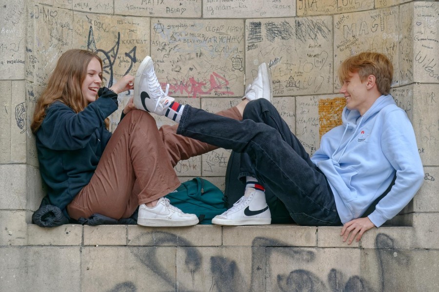 Two kids sitting on a graffiti-covered wall