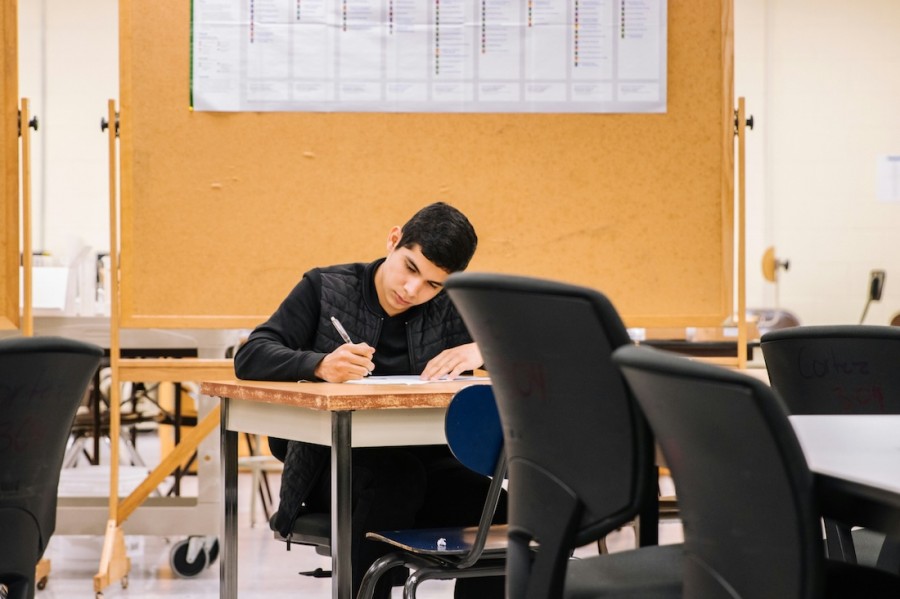 A young student diligently writing at a classroom table