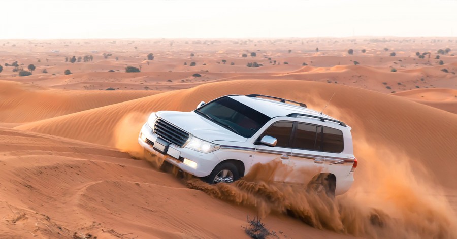 A white SUV cruising through the vast desert landscape, perfect for a Dubai road trip adventure