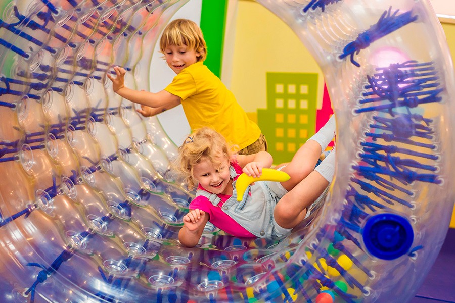 Two children joyfully playing inside a colorful inflatable ball at a kid-friendly museum in Dubai