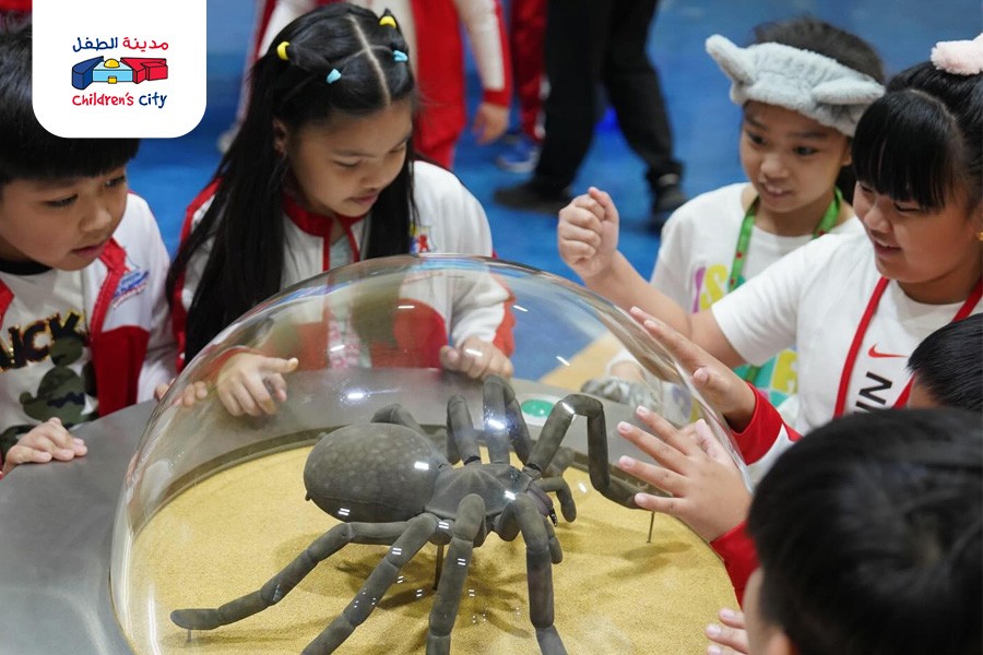 Children observe a spider inside a glass case at a kid-friendly museum in Dubai