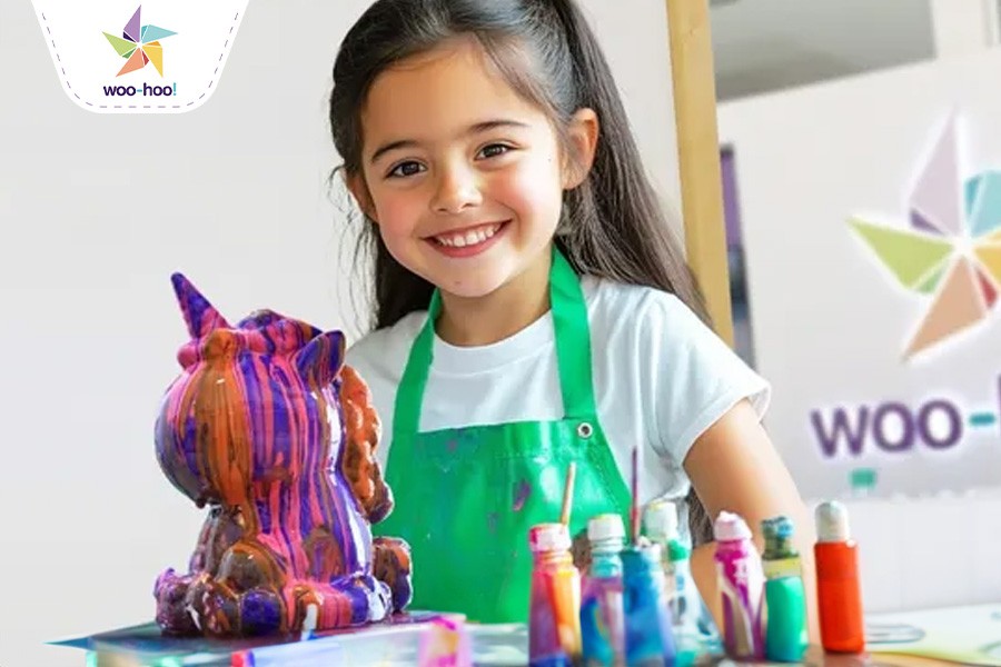 A young girl smiles while holding a colorful unicorn sculpture at a kid-friendly museum in Dubai