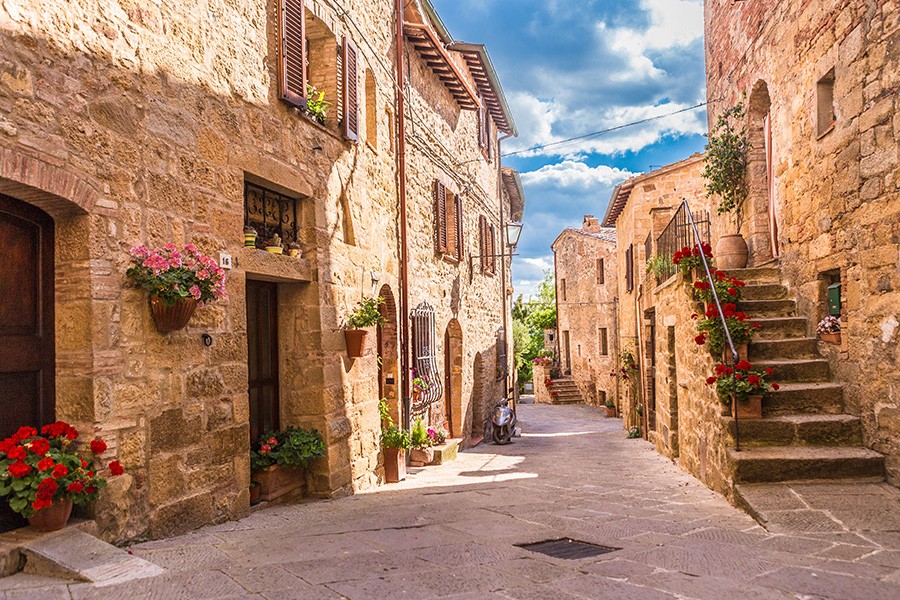 A narrow street in an Italian village, featuring charming stone buildings, captured during a holiday in Siena.