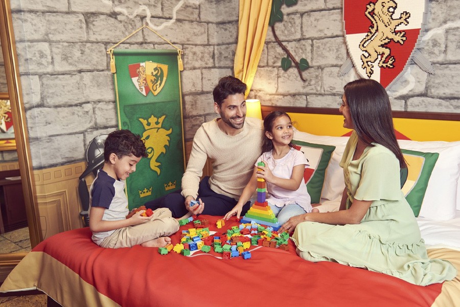 A family joyfully builds with LEGO blocks in a castle-themed room at LEGOLAND's family-friendly hotel in Dubai