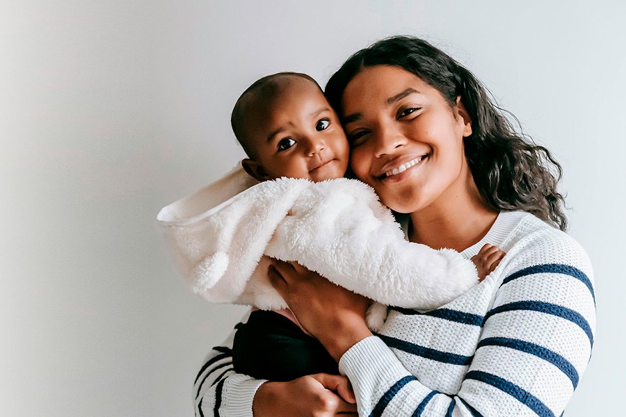 A woman lovingly cradles a baby in her arms, smiling gently at the child