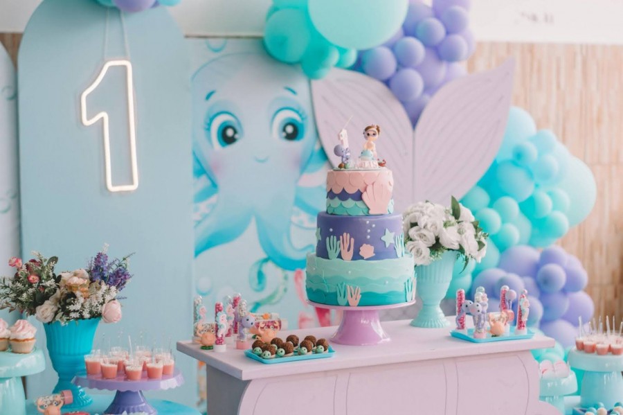 A vibrant birthday party featuring a mermaid theme, with decorations, cake, and guests in festive attire