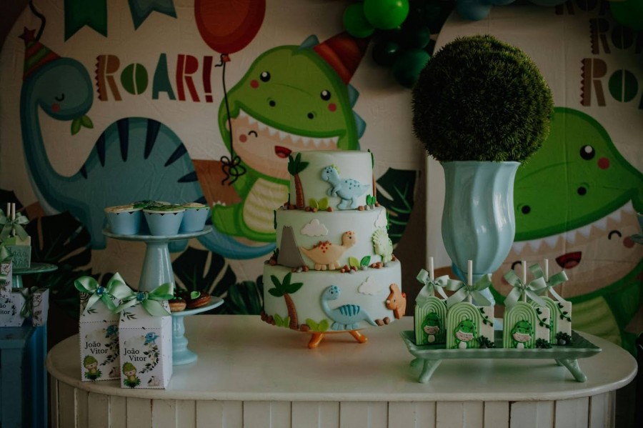 A dinosaur-themed birthday party featuring a colorful cake, cupcakes, and festive decorations