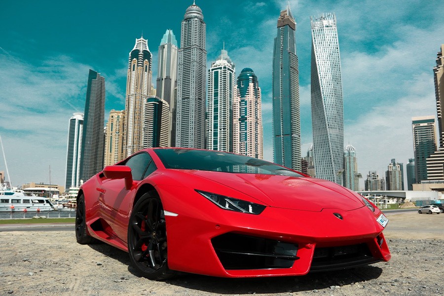 A red sports car parked in front of tall urban buildings, showcasing a vibrant cityscape