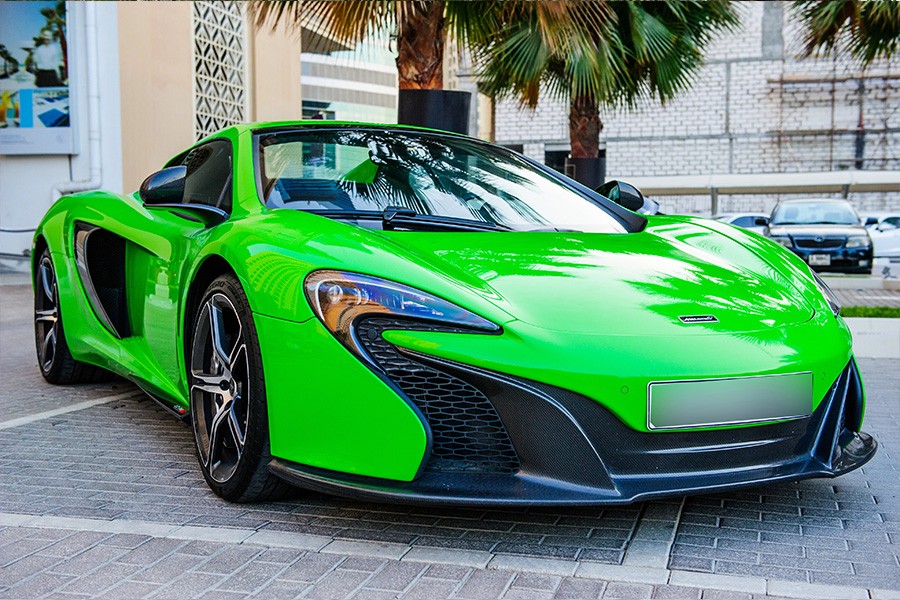 A bright green McLaren sports car parked in front of palm trees, promoting luxury car rentals in Dubai