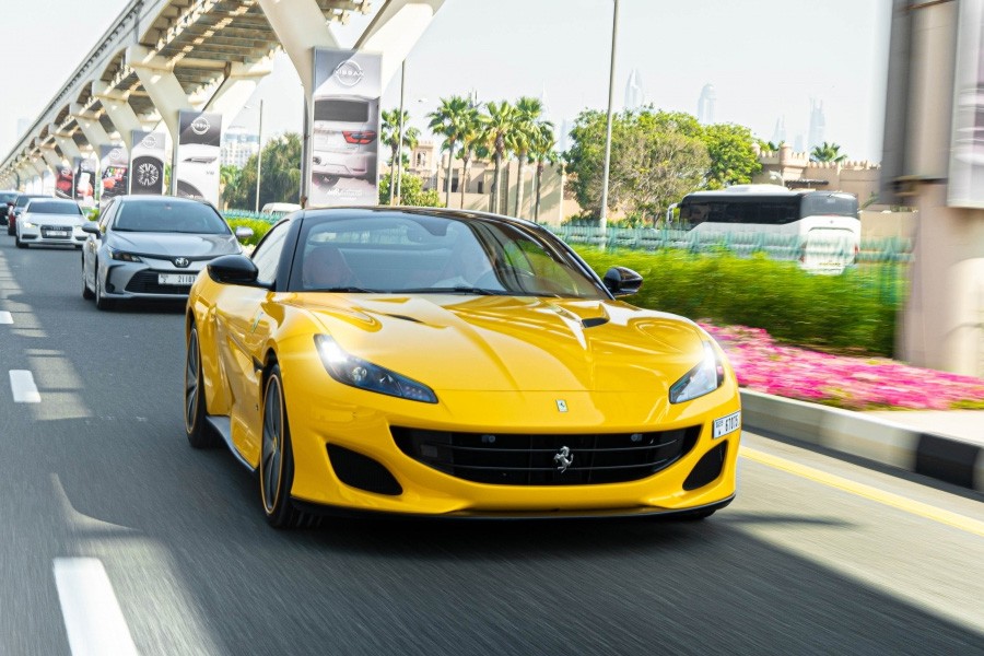 A yellow sports car speeds down a highway in Dubai, showcasing its sleek design against the urban landscape