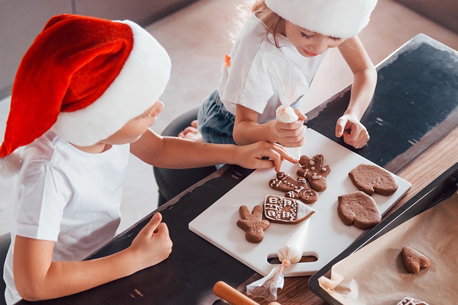 Two children in Santa hats joyfully decorating cookies during a magical Christmas event for kids in the UAE