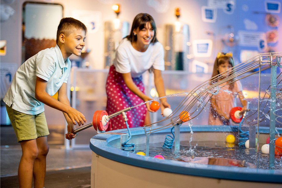 A family enjoys water toys together in an indoor exhibit, showcasing fun weekend activities for kids