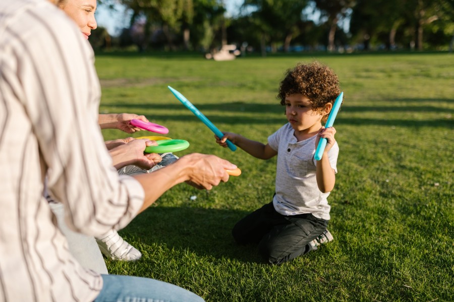 A parrents and a child joyfully playing with colorful toys on a sunny day in the park