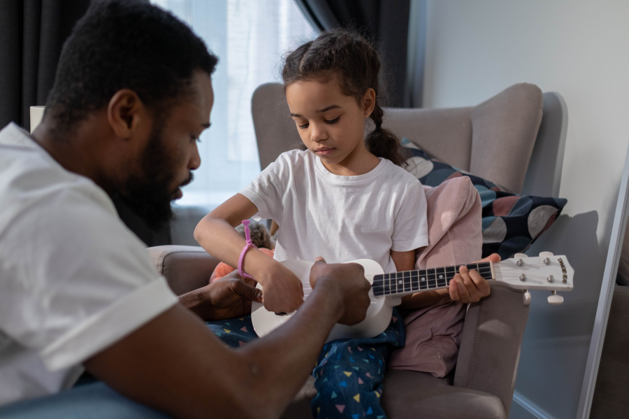 A father and daughter joyfully playing a ukulele together, sharing a musical moment in a cozy setting